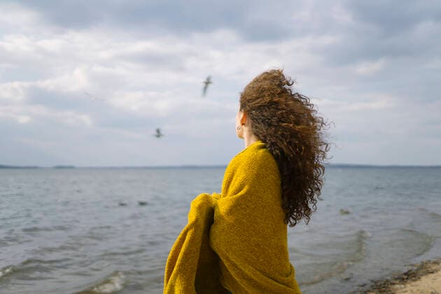 Creative Highlights Symbolbilder a woman stands on the shore of the lake covered with a yellow cape Minsk, Minsk Region, Belarus CR_ALLI2203160F-719043-01 ,model released, Symbolfoto