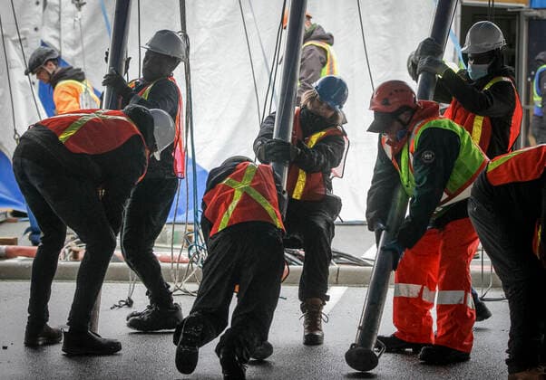 (220319) -- VANCOUVER, March 19, 2022 -- Workers push the supporting poles to raise the big top to its final position for the Cirque du Soleil s upcoming show Alegria at Concord Pacific Place in Vancouver, British Columbia, Canada, on March 18, 2022. More than 60 workers pushed over 100 supporting poles to raise the canvas into its final position in order to set up the the iconic Big Top - where the main stage of Cirque du Soleil will take place. (Photo by Xinhua) CANADA-VANCOUVER-CIRQUE DU SOLEIL-BIG TOP-RAISING LiangxSen 