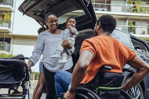 Mother carrying son looking at father in wheelchair by car model released, MFF08526