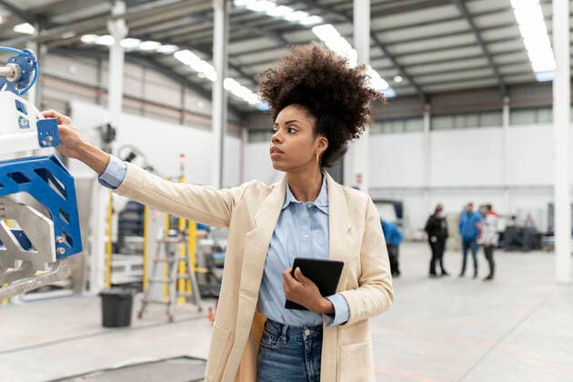 IMAGO Creative: Business, Inflation und Lieferketten Businesswoman holding tablet PC analyzing machine in factory model released property released, JCCMF05593