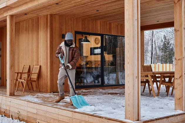 Man shoveling snow from porch outside house in winter model released property released, DSHF00179