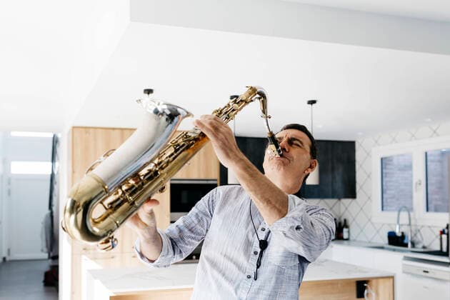 IMAGO Creative: 2022 Favoriten Passionate saxophonist practicing saxophone in kitchen at home model released property released, JRFF05340