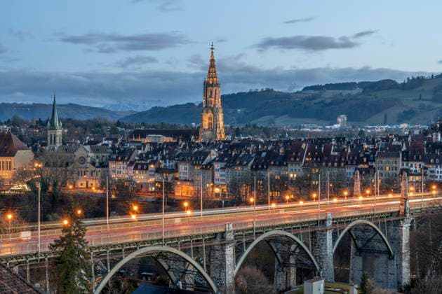 Switzerland, Canton of Bern, Bern, Kornhausbrucke bridge at dusk with bell tower of Cathedral of Bern in background, KEBF02253