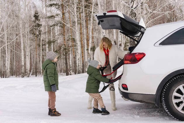 IMAGO Creative: Countdown bis Weihnachten, Nach Hause reisen Woman helping son removing toboggan from car trunk win winter forest model released, SEAF00657