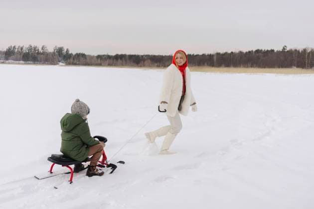 Woman looking at son sitting on toboggan enjoying in winter model released, SEAF00690