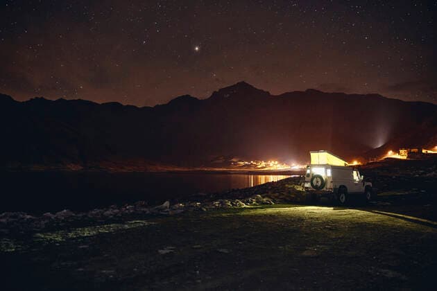 Illuminated off-road vehicle by reservoir at night, Splugen Pass, Sondrio, Switzerland property released, SSCF00853