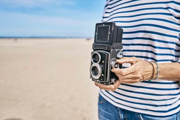 Woman with vintage camera standing at beach model released, SSCF01014