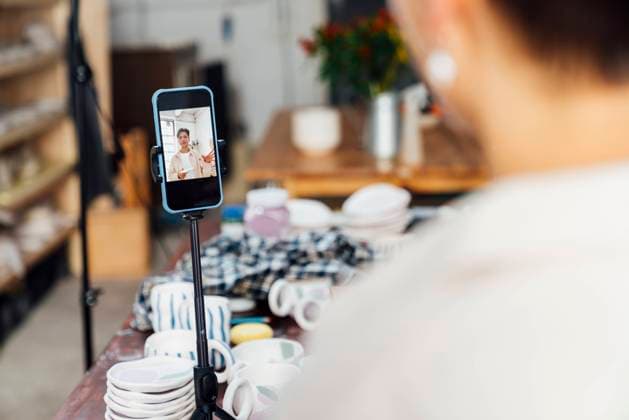 Influencer filming vlog through smart phone on tripod model released property released, VPIF05578