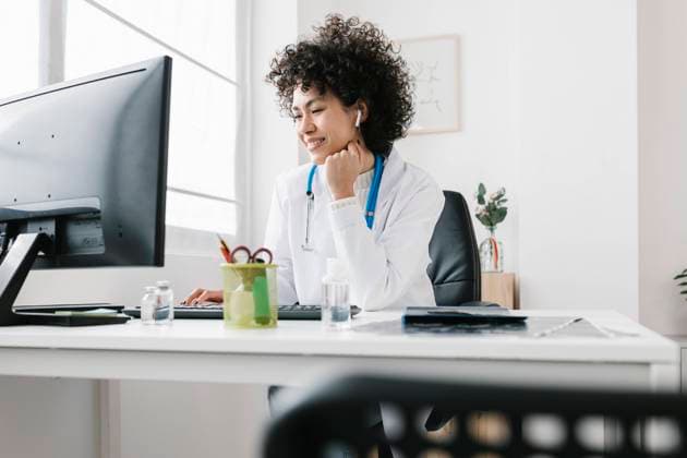 Doctor sitting with hand on chin using desktop PC at clinic model released property released, XLGF02751