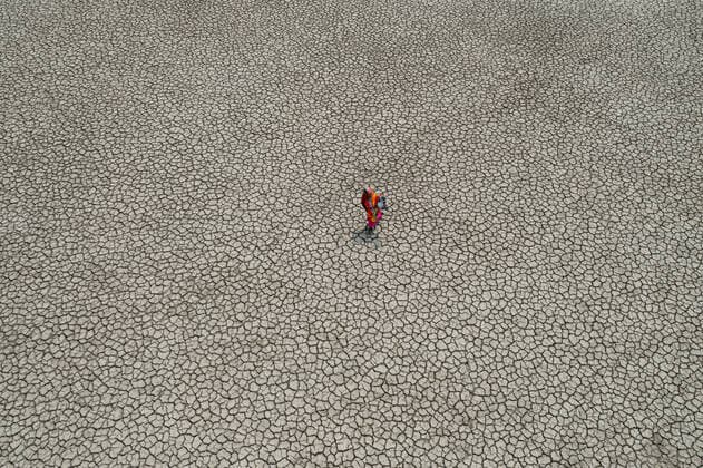 Climate Change In Bangladesh A woman walks into a deep cracks field after collecting drinking water from a pond near mangrove forest Sundarban in Satkhira, Bangladesh on March 27, 2022. Dhaka Bangladesh  Copyright: xKazixSalahuddinxRazux originalFilename: salahuddin-notitle220329_npBOv.jpg