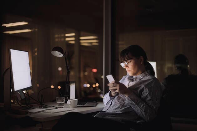 Businesswoman text messaging on smart phone sitting at work place Sweden, Stockholm, model released, property released Copyright: xMaskotx , MA92818