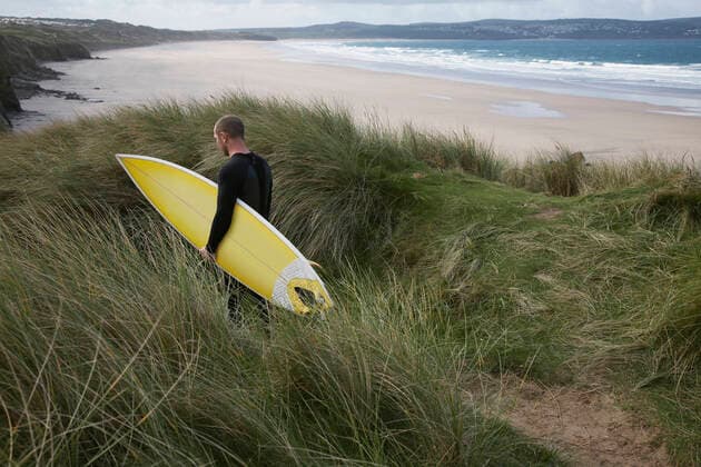 IMAGO Creative: 2022 Sport Favoriten Creative Highlights Symbolbilder Man With Surfboard Walking Through Grass On Beach, model released, , 10038034.jpg, Activity, Adult, Adventure, Beach, Carrying, Caucasian, Coastline, Cornwall, Day, Hobbies, Hobby, Horizontal, Leisure, Lifestyle, Long Grass, Male, Man, Men, Ocean, One, Outdoors, People, Person, Rear View, Recreation, Recreational, Sea, Seaside, Sport, Summer, Surf, Surfboard, Surfer, Vacation, Walking, Water, Watersport, Weekend, Wetsuit, 30s,