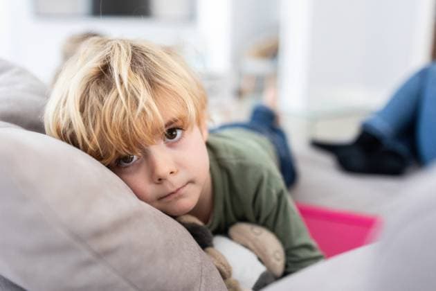 Unhappy boy with blond hair looking away while lying on comfortable gray sofa with toy in light living room on blurred background, Model released AngelSantamaria_DigitalDependency_10.jpg Copyright: xAngelxSantamariax MR