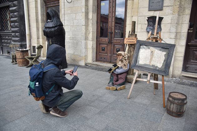 April 3, 2022, Lviv, Ukraine: A man photographs a mannequin of a medieval prisoner with a portrait of Russian President Vladimir Putin at the entrance to a Lviv cafe. Due to Russia s military invasion of Ukraine, a mannequin of a medieval prisoner with the head of the occupying power, President Vladimir Putin, placed in medieval torture - the sinner s violin - was placed near Lviv cafe Lviv Ukraine - ZUMAs197 20220403_zaa_s197_402 Copyright: xPavloxPalamarchukx