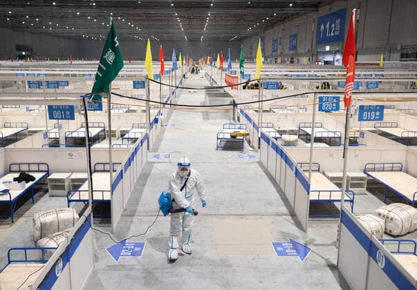 (220409) -- SHANGHAI, April 9, 2022 -- A staff member disinfects the construction site of a temporary hospital at the National Exhibition and Convention Center (Shanghai) in east China s Shanghai, April 8, 2022. Shanghai has opened and will continue to construct more temporary hospitals to enhance the city s treatment capacity for COVID-19 infections in its latest COVID-19 resurgence, authorities said Friday. Four municipal-level temporary hospitals, three located in Pudong District and one in Chongming District, have been put into use as of Friday. Covering a total of 500,000 square meters, the four sites can offer a total of 38,000 beds, said Jin Chen, deputy director of Shanghai s housing and urban-rural development management com