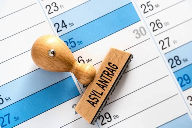 11 April 2022: Stamp of wood on a calendar with the inscription Asylum application PHOTOMONTAGE *** Stempel aus Holz auf einem Kalender mit der Aufschrift Asyl Antrag FOTOMONTAGE