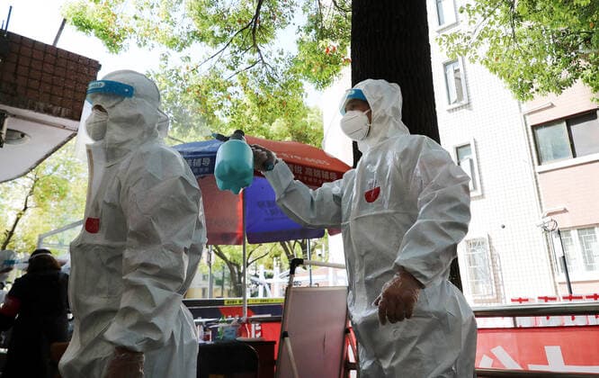 (220412) -- SHANGHAI, April 12, 2022 -- Shi Zhongliang (R) sprays disinfectants on the protective gear of his teammate in east China s Shanghai, April 11, 2022. Shi Zhongliang, a resident of Qibao Township, Minhang District of Shanghai, now renders his service as a volunteer in his community. His residential community has been under closed-off management since March 18 due to the resurgence of COVID-19. Soon after that, Shi joined the community volunteer team spontaneously organized by the residents from the same community. The team, with only seven members from the start, has grown as big as 40 within a month. Shi and his teammates are mainly responsible for delivering the living materials purchased online by the residents. To