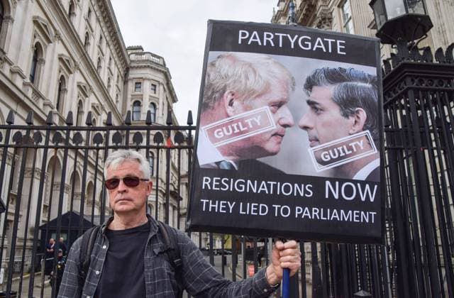 April 13, 2022, London, England, United Kingdom: A protester holds a sign calling Boris Johnson and Rishi Sunak guilty and calling for their resignations. Protesters gathered outside Downing Street demanding that Prime Minister Boris Johnson and Chancellor of the Exchequer Rishi Sunak resign. The two politicians received fines over parties held at Downing Street during covid lockdown, known as Partygate , and have stated that they have no intention of resigning despite the scandal. London United Kingdom - ZUMAv130 20220413_zip_v130_001 Copyright: xVukxValcicx