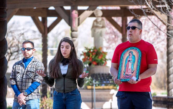 April 15, 2022, USA: From left, Jacob Maestas, Evelyn Juarez and Nathan Torrez, all with Las Palmas Youth Adult Ministries in Espanola, pray behind the Santuario de Chimayo after their Good Friday Pilgrimage. After two years of almost no Good Friday Pilgrimage thousands made the treck this year to the northern New Mexico church, Friday April 15, 2022. USA - ZUMAab1_ 20220415_zaf_ab1_018 Copyright: xEddiexMoorex