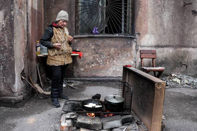 News Themen der Woche KW15 News Bilder des Tages Ukraine-Konflikt, EindrÃ¼cke aus Mariupol MARIUPOL, DONETSK REGION, UKRAINE - APRIL 16, 2022: A woman cooks food outside a residential building. The Russian Armed Forces are carrying out a special military operation in Ukraine. Sergei Bobylev TASS  TS12CF0D