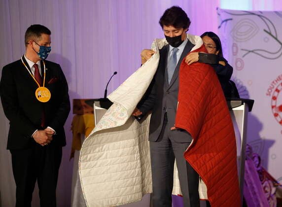 April 22, 2022, WINNIPEG, MANITOBA, CANADA: Southern Chiefs Organization gives a blanket to Prime Minister Justin Trudeau as Mayor Brian Bowman looks on at a HudsonöÄÃ s Bay Company transfer ceremony in Winnipeg Friday, April 22, 2022. One of the landmark stores formerly run by the HudsonöÄÃ s Bay Company is about to undergo a major transformation in the name of reconciliation with Indigenous people. WINNIPEG CANADA  - ZUMAc35_ 20220422_zaf_c35_029 Copyright: xJohnxWoodsx