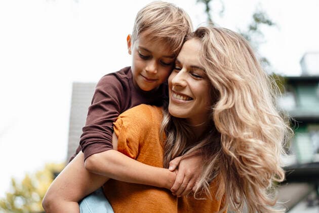 Happy blond woman giving piggyback ride to son at backyard model released, Symbolfoto property released, JOSEF08229