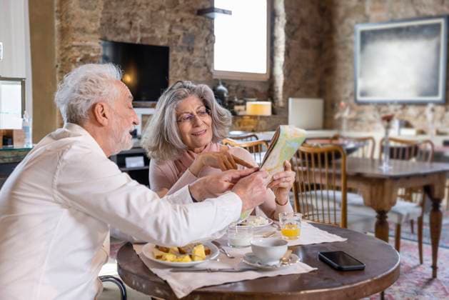 Senior man showing city map to woman sitting at breakfast table in boutique hotel model released, Symbolfoto property released, EIF03713