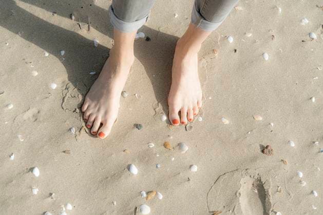 Woman standing barefeet on sand with seashells at beach model released, Symbolfoto, CHPF00845