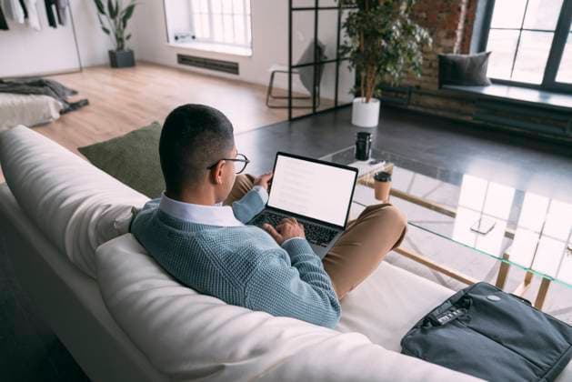 Freelancer using laptop sitting on sofa in living room at home model released, Symbolfoto property released, VPIF05742