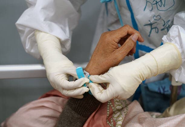(220424) -- SHANGHAI, April 24, 2022 -- A medical worker puts on a wristband for a senior patient in a makeshift hospital in Shanghai, east China, April 23, 2022. The makeshift hospital in Lingang is converting around 2,000 beds to treat COVID-19 patients with moderate symptoms and senior patients over 80 years old. ) CHINA-SHANGHAI-MAKESHIFT HOSPITAL (CN) YangxYouzong 