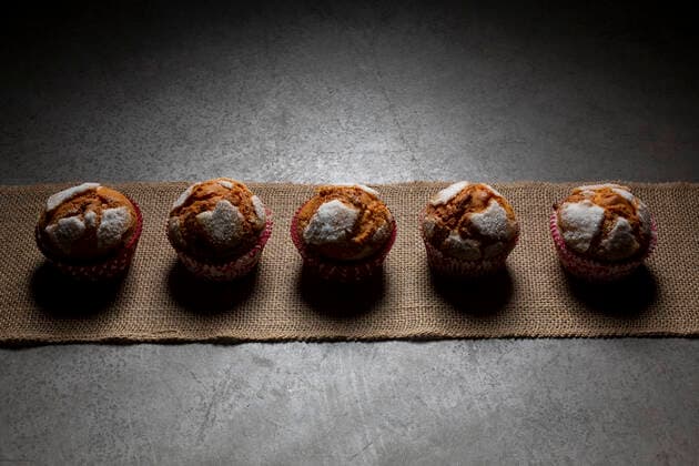 IMAGO Creative: 2022 Favoriten Top view of sweet freshly baked muffins with powdered sugar arranged in row on textile on gray background in light kitchen Copyright: xSinuxMorax Model Released