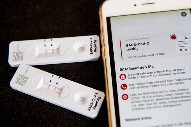 Bamberg, Deutschland 28. April 2022: Themenbilder - Symbolbilder - Coronavirus - 2022 Auf einem Tisch liegt ein Antigen-Schnelltest auf das Coronavirus SARS-CoV-2 dieser das Ergebnis Positiv anzeigt, daneben liegt ein Handy mit der Mitteilung das das Ergebnis des PCR Test Befundes auch Positiv ist. Bayern Copyright: xFotostandx xK.xSchmittx
