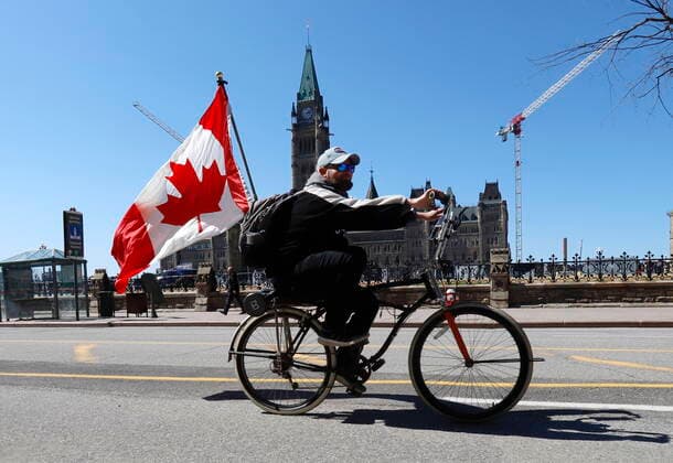 April 29, 2022, Ottawa, ON, Canada: A man rides a bicycle in front of the Parliament Buildings before the arrival of the Rolling Thunder motorcycle convoy protest in Ottawa on Friday, April 29, 2022. Ottawa Canada  - ZUMAc35_ 20220429_zaf_c35_071 Copyright: xPatrickxDoylex