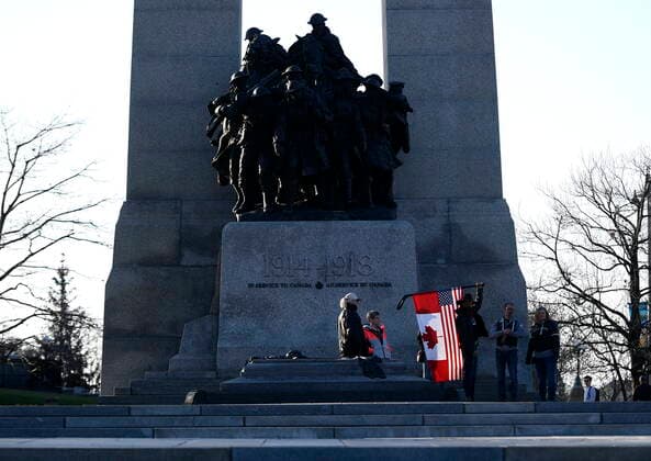 April 29, 2022, Ottawa, ON, CAN: A person holds a combination American and Canadian flag at the Tomb of the Unknown Soldier at the National War Memorial before a march at a demonstration, part of a convoy-style protest participants are calling Rolling ThunderöÄÃ¹, in Ottawa, on Friday, April 29, 2022. Ottawa CAN  - ZUMAc35_ 20220429_zaf_c35_095 Copyright: xJustinxTangx