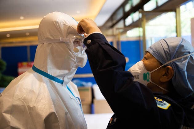(220510) -- SHANGHAI, May 10, 2022 -- Zhang Ying (R) helps Meng Xiangjun wear protective suit at the headquarters of a medical emergency team on Caoyang Road in east China s Shanghai, May 9, 2022. A medical emergency team consisting of 108 members with 50 ambulances from north China s Tianjin has arrived at Shanghai to assist in the city s public medical emergency service amid the COVID-19 resurgence. ) CHINA-SHANGHAI-MEDICAL TEAM-COVID-19-AID (CN) JinxLiwang 