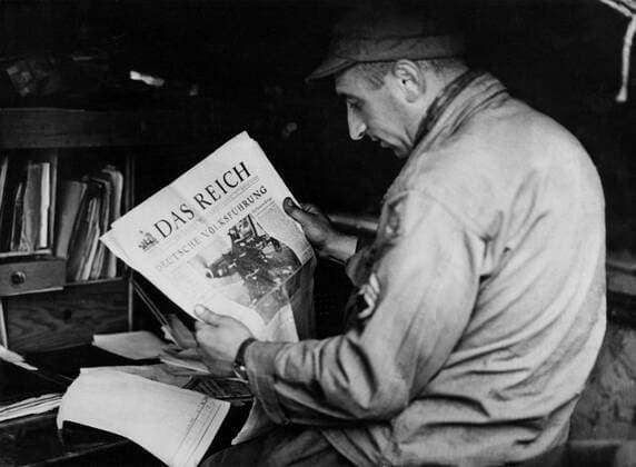 An American soldier read a Nazi newspaper in Carentan (France) June 1944 U.S. Army Staff sergeant reads a captured Nazi newspaper near Carentan in Normandy (France) June 1944. Copyright: xPhoto12 Coll-DITE USISx DIT01079_244