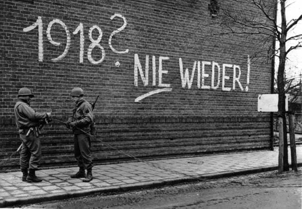 A German propaganda sign in Echt (Holland) February 1945. Signalmen of the 9th U.S. Army repair communications wires in the liberated town of Echt (Holland) in February 1945,beside a building bearing a German propaganda sign . 1918? nie wieder (never again) Copyright: xPhoto12 Coll-DITE USISx DIT01138_027