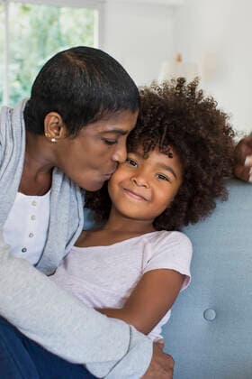 Creative Highlights Symbolbilder Grandmother kissing granddaughter in living room Copyright: Anne-SophiexBost B32528740