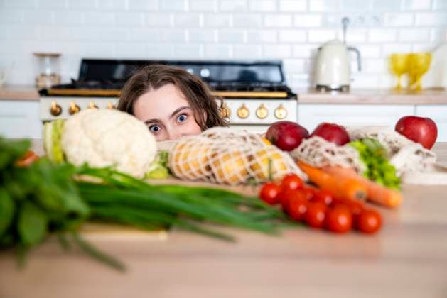 Woman hiding behind vegetables on dining table in kitchen model released, Symbolfoto property released, VPIF05846