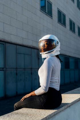 Creative Highlights Symbolbilder Young businesswoman with space helmet sitting on wall model released, Symbolfoto, MEUF05210