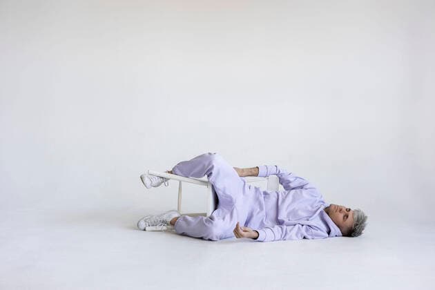 Creative Highlights Symbolbilder Man with chair lying on white floor model released, Symbolfoto property released, LHPF01414