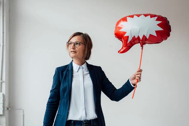 Creative Highlights Symbolbilder Businesswoman with speech bubble on red balloon in front of wall at office model released, Symbolfoto property released, JOSEF09171