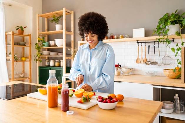 Smiling woman cutting fruit on board in kitchen at home model released, Symbolfoto property released, OIPF01715