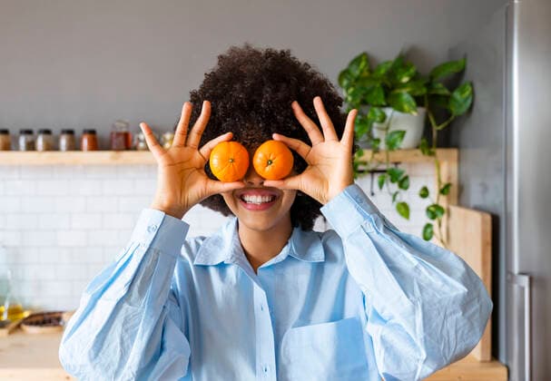 Creative Highlights Symbolbilder Young woman holding oranges in front of eyes at home model released, Symbolfoto property released, OIPF01728
