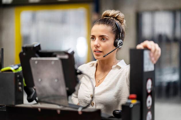 IMAGO Creative: Business, Inflation und Lieferketten Young businesswoman wearing headset operating machine in factory model released, Symbolfoto property released, PESF03754