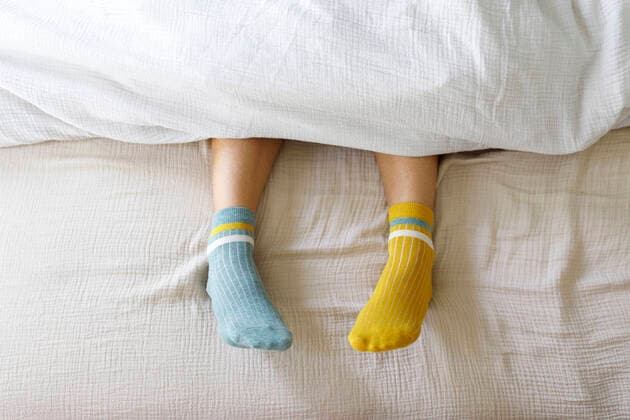 Creative Highlights Symbolbilder Woman wearing blue and yellow socks in bed at home model released, Symbolfoto property released, TYF00144