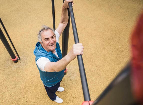 Creative Highlights Symbolbilder Smiling senior man holding gymnastics bar at park model released, Symbolfoto, UUF26070