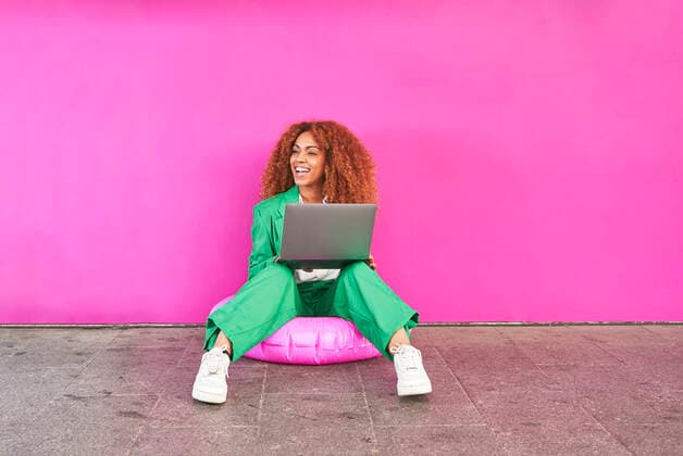 Creative Highlights Symbolbilder Happy businesswoman holding laptop sitting on inflatable ring in front of pink wall model released, Symbolfoto, VEGF05621