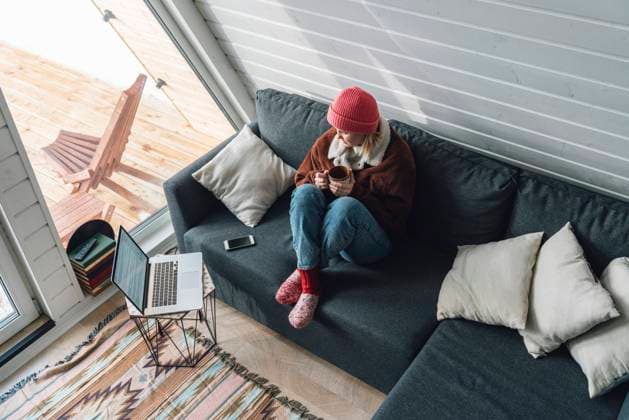 IMAGO Creative: Herbst, Gemütliches Zuhause Woman watching laptop sitting on sofa with drink at home model released, Symbolfoto property released, VPIF05948