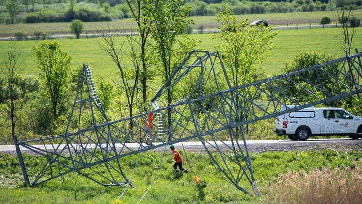 May 24, 2022, Ottawa, ON, CAN: A utility worker passes the top segment of a transmission tower, lying on the ground, after it was damaged in SaturdayöÄÃ s major storm in Ottawa, on Tuesday, May 24, 2022. Ottawa CAN  - ZUMAc35_ 20220524_zaf_c35_025 Copyright: xJustinxTangx